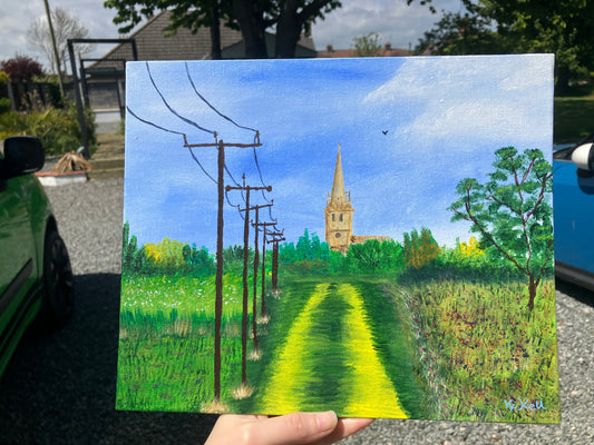 An acrylic landscape painting on canvas board of a church in the distance and telegraph poles in the foreground to the left. the sky is a mid to light blue with white fluffy clouds and the are green field at either side with a yellow-green path leading up to a row ow trees that run across the full painting in front of the church. There is a leafy green tree to the right of the painting with a brown trunk. There is a small single bird flying in the sky above and to the right of the church steeple.