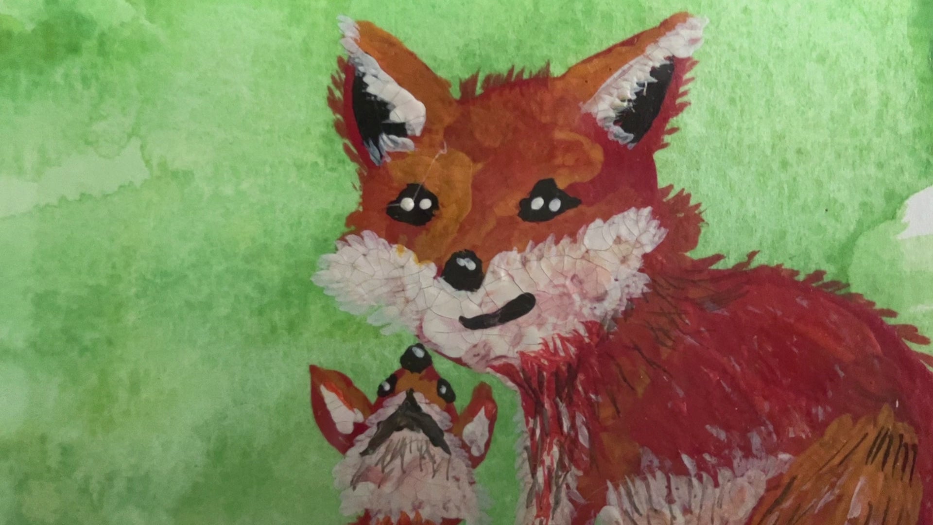video of a watercolour painting of a red fox and baby with green splash background in a frame on a mantlepiece. 